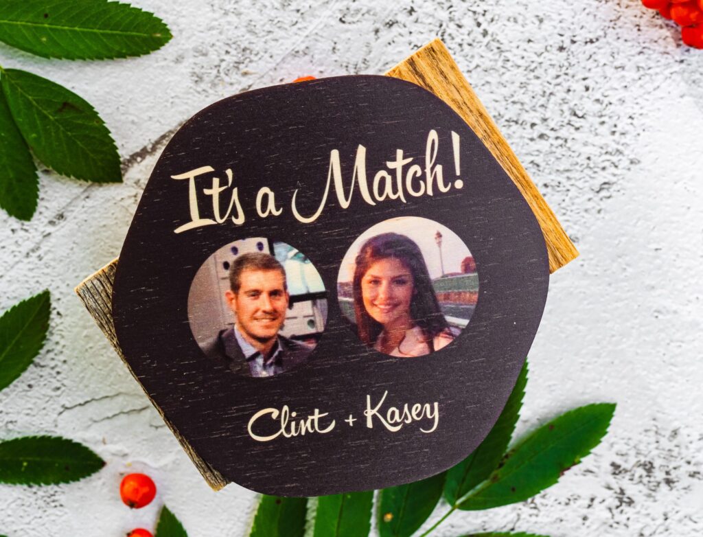 A coaster with pictures of two people.
Text above reads: "It's a match!"
Text below reads: "Clint + Kasey"